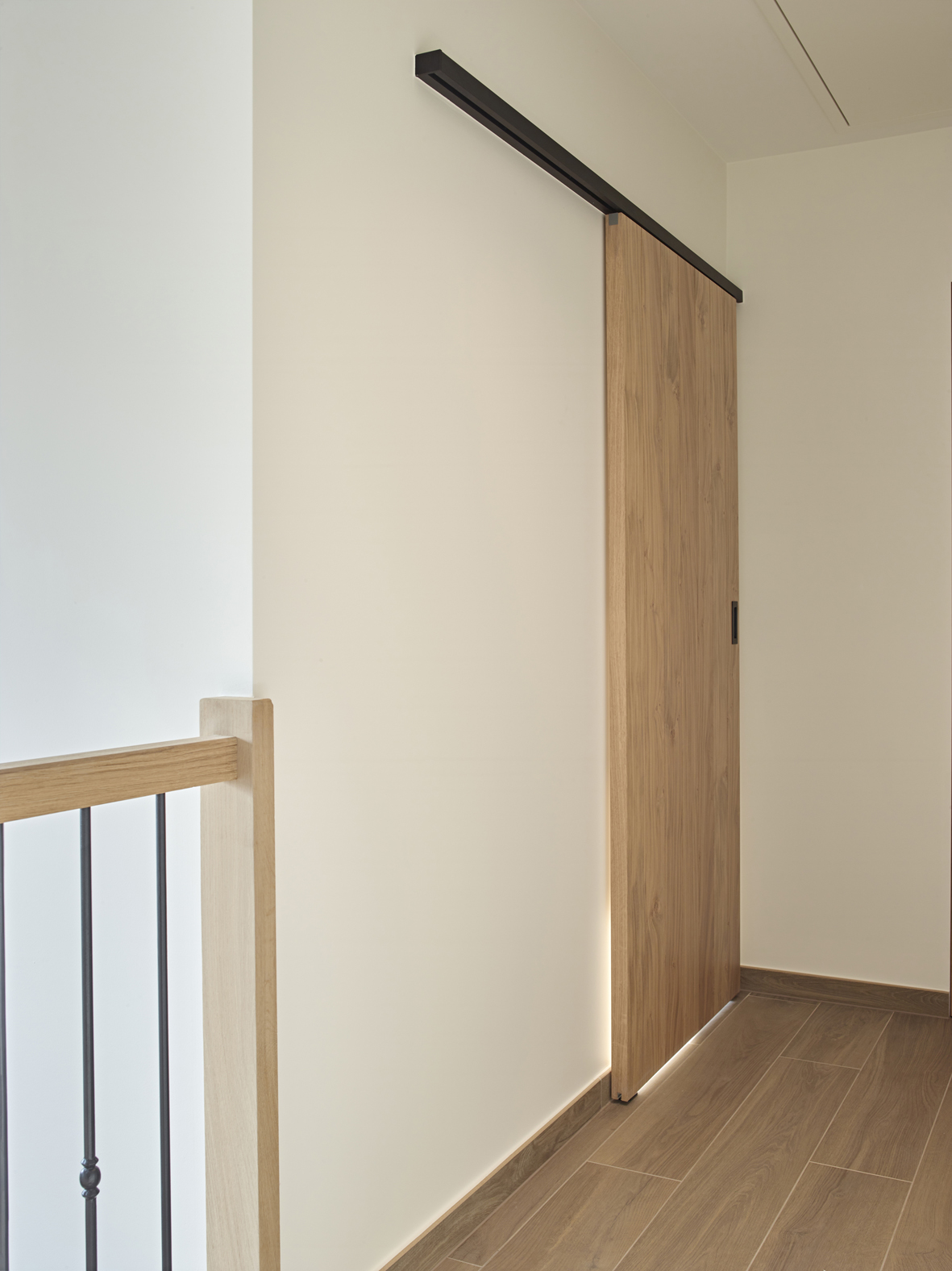 Houten schuifdeur bevestigd met zwarte aluminium muurbevestiging van ARLU (Argenta). 