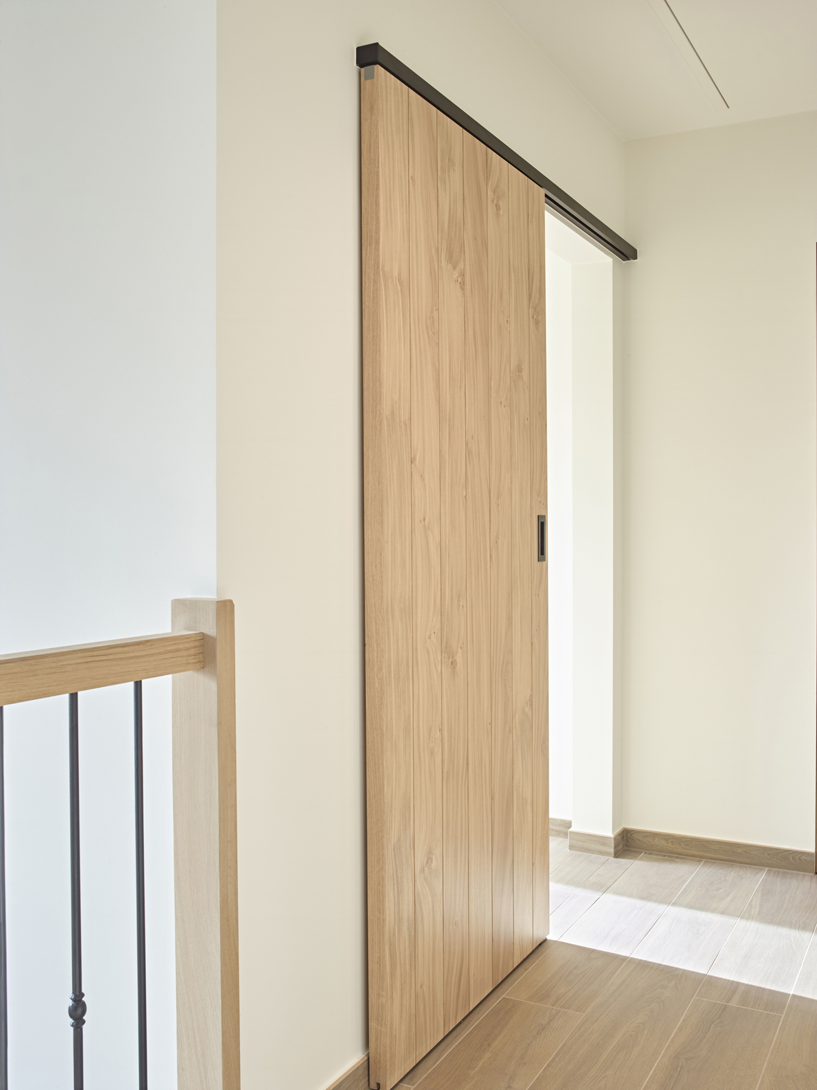 Houten schuifdeur bevestigd met zwarte aluminium muurbevestiging van ARLU (Argenta). 