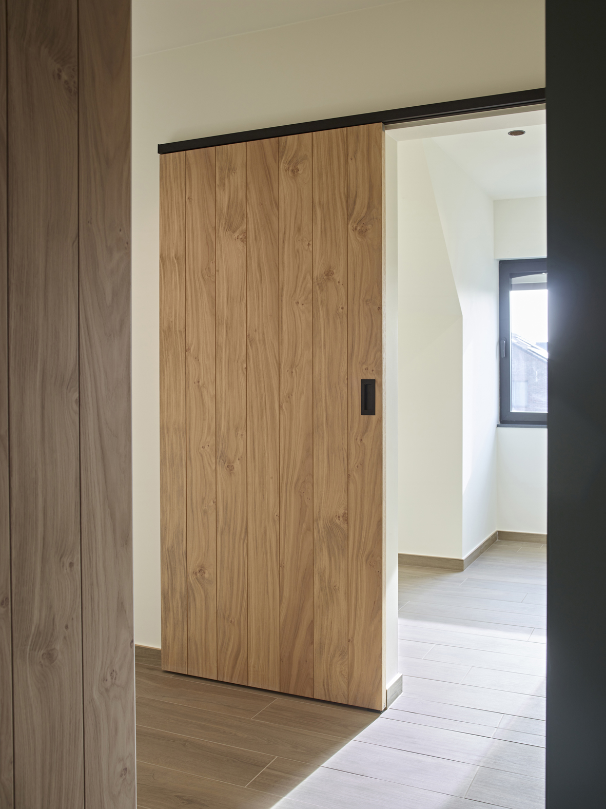 Houten schuifdeur bevestigd met zwarte aluminium muurbevestiging van ARLU (Argenta). 