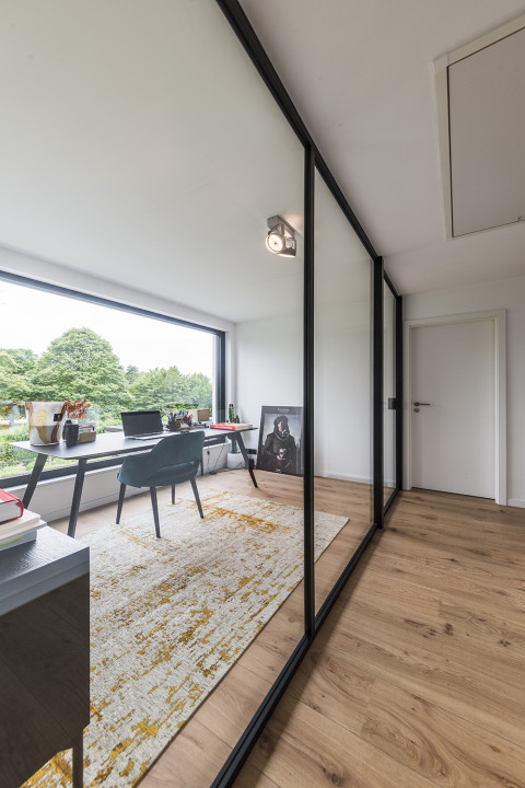 Séparation entre le bureau et le hall sans perte de lumière et d'ouverture grâce à la divina d'ARLU - une paroi de séparation en verre avec une porte battante en verre.