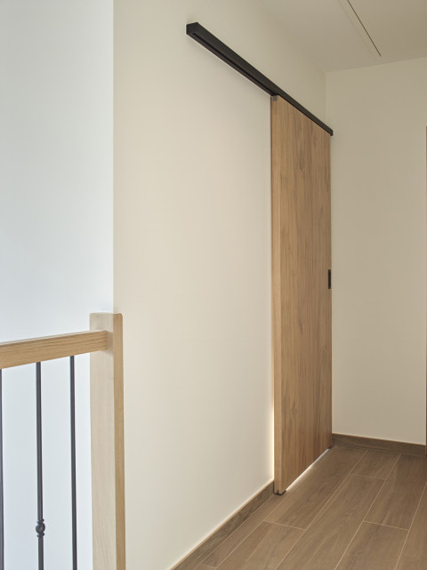 Houten schuifdeur bevestigd met zwarte aluminium muurbevestiging van ARLU (Argenta). 