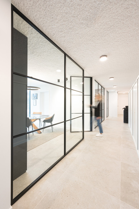 Zwarte glazen scheidingswand gecombineerd met glazen draaideur (product: divina ARLU) geïnstalleerd bij MFI Coatings.