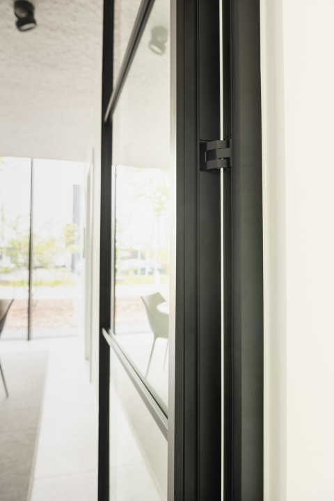 Zwarte glazen scheidingswand gecombineerd met glazen draaideur (product: divina ARLU) geïnstalleerd bij MFI Coatings.
